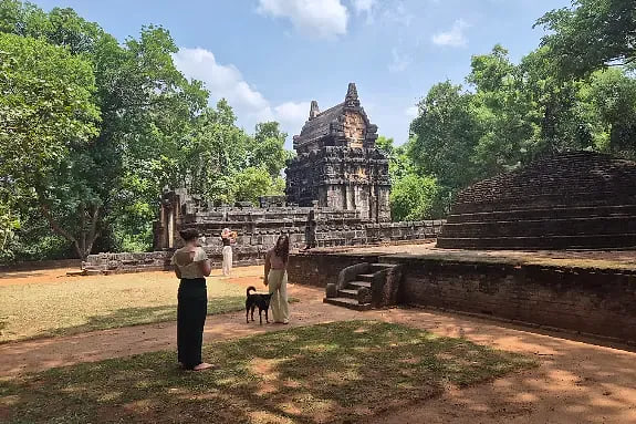 A brick stupa and stone ruins standing in open ground at Polonnaruwa