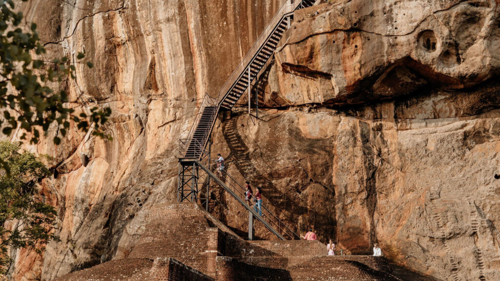 Visitors climbing the staircase up the rock face at Sigiriya