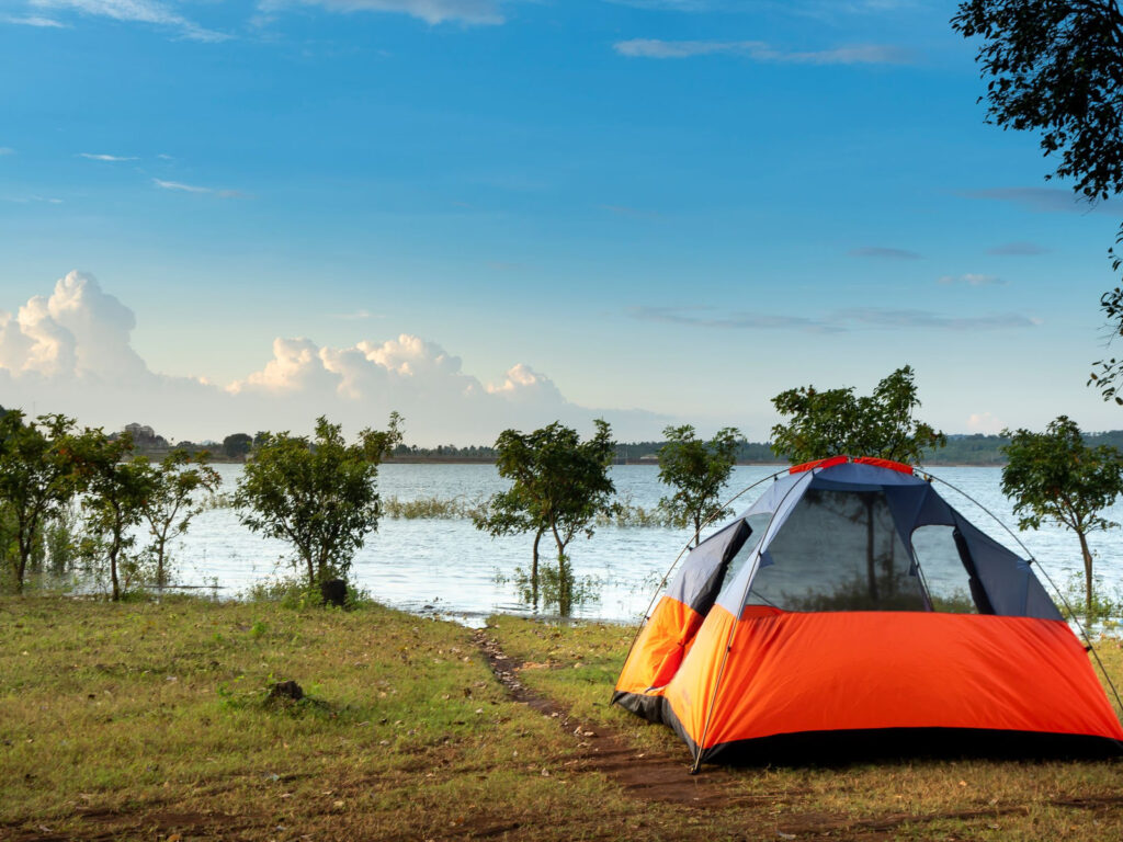 A tent pitched on the grassy shore of a lake