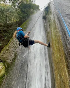 A traveller abseiling down a wet rock face