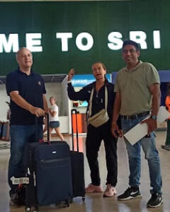 A guide meeting guests under a Welcome to Sri Lanka sign at the airport