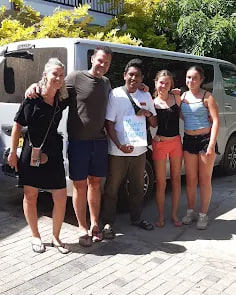 A family standing with their guide beside the tour van