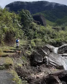 A walker on a stone trail climbing through the hills