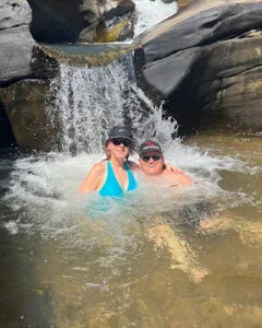 Two travellers in the pool below a waterfall