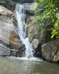 A traveller standing in the spray at the foot of a waterfall