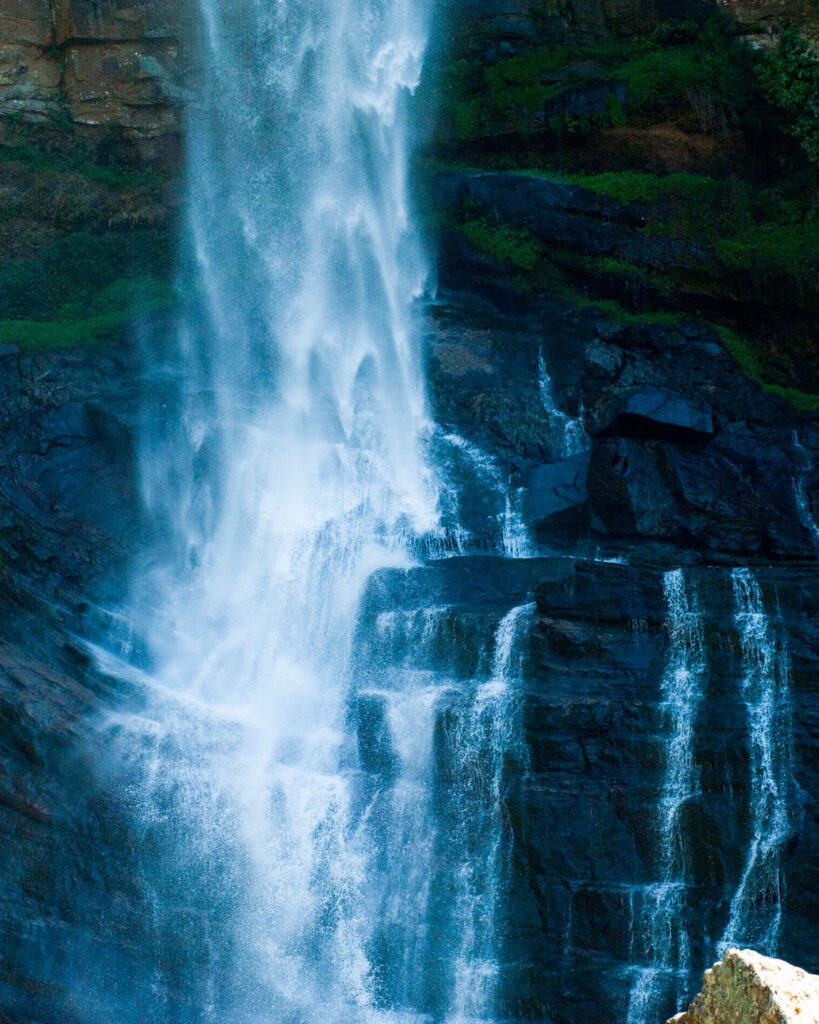 A tall waterfall tumbling down a dark rock face in the hill country