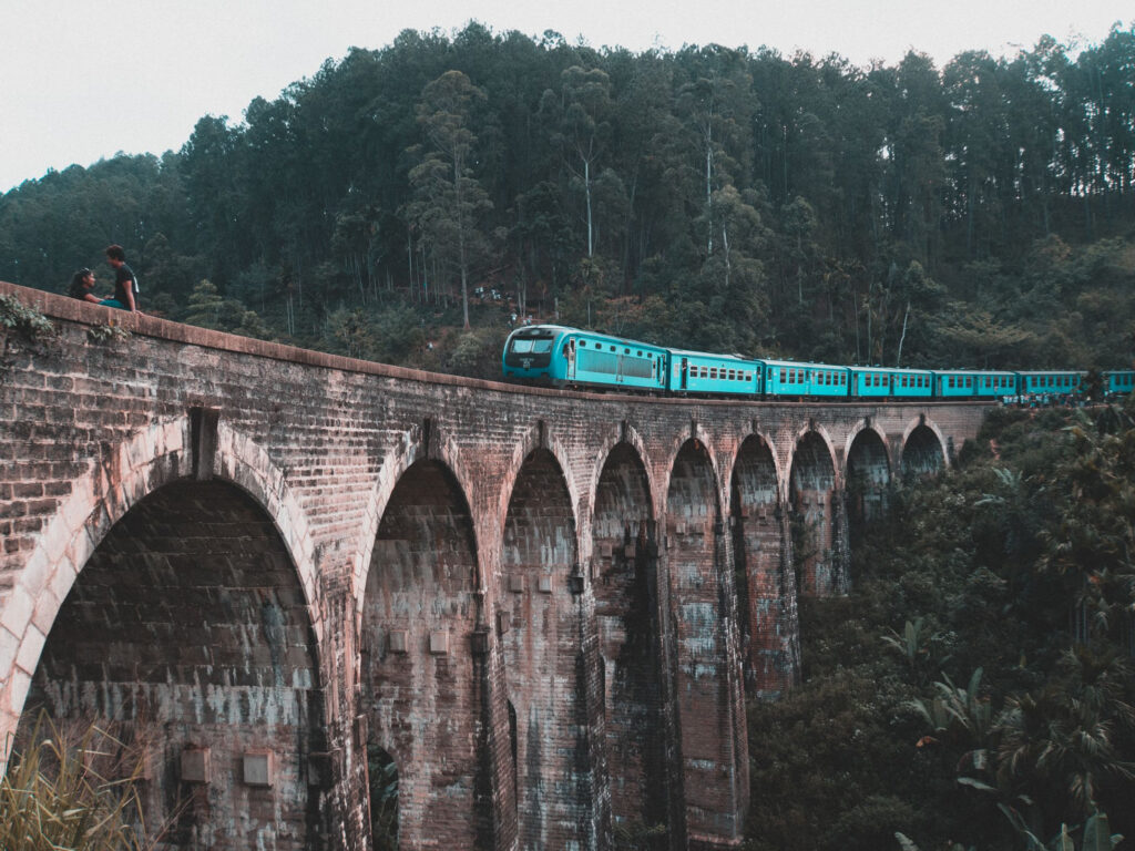 A turquoise train crossing the Nine Arch Bridge at Ella
