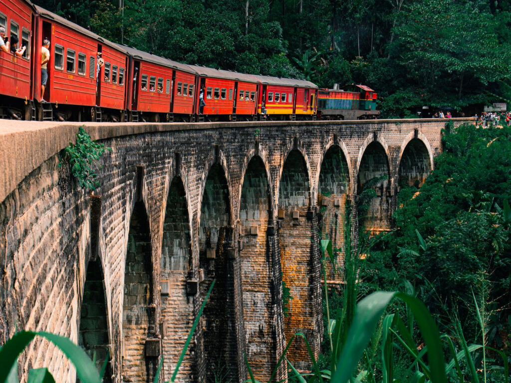 A red train crossing the Nine Arch Bridge in Ella